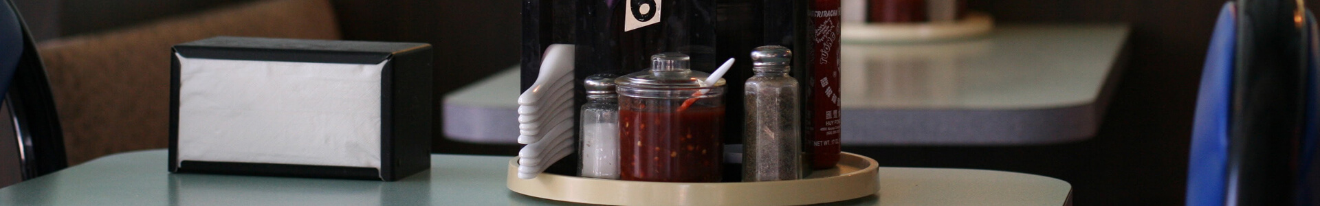 Spices and napkins in holders on a restaurant table.