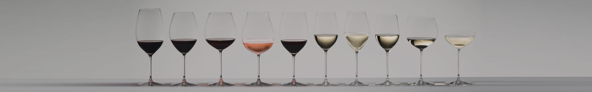 Numerous wine glasses and other stemware from the Riedel Veritas series stand next to each other.