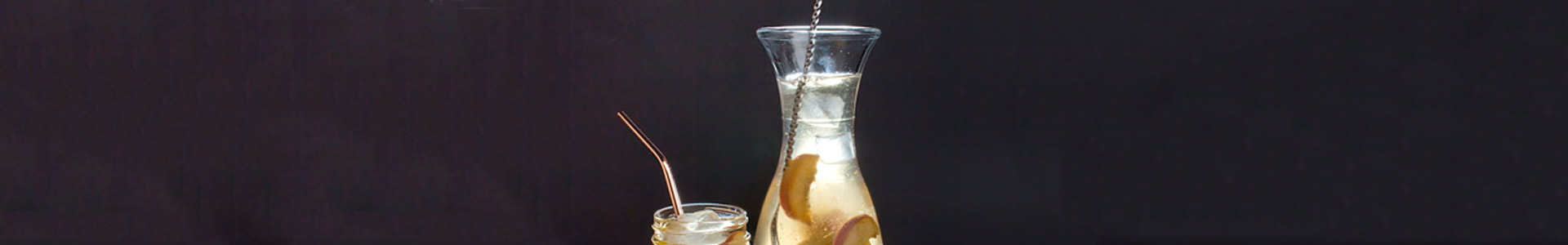 Glass carafe filled with juice and peach slices.