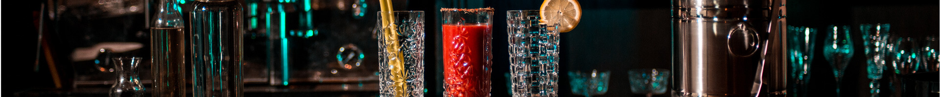 Three long drink glasses with different designs stand next to each other.