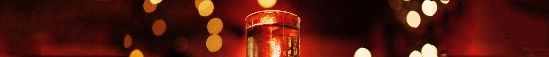 Filled shot glass in red-gold light.
