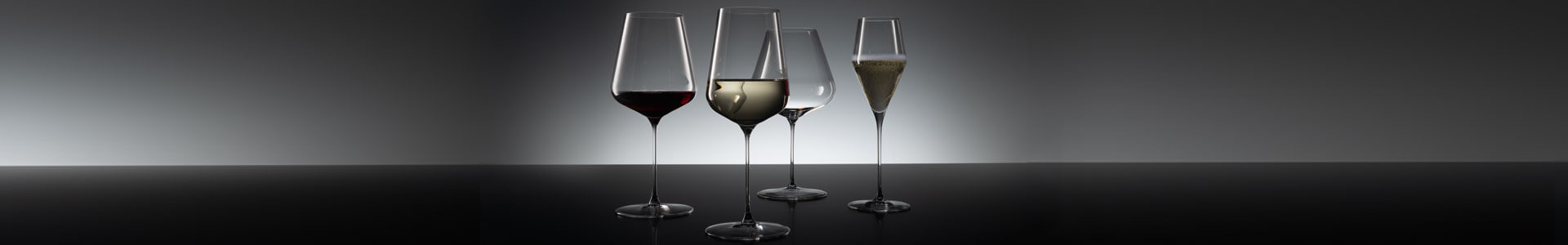 Wine glasses from Spiegelau stand on a dark surface.